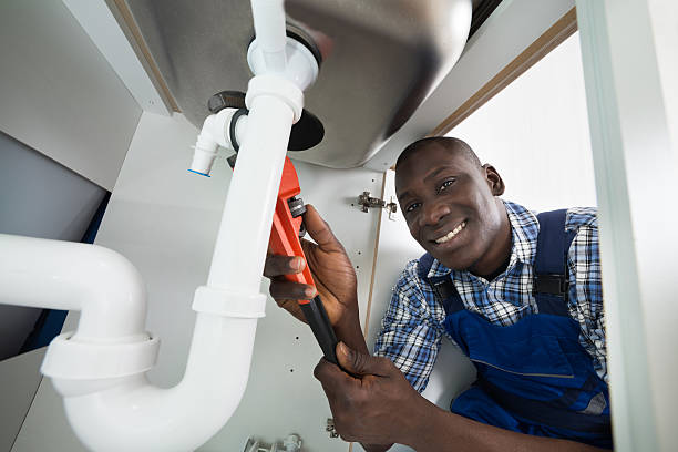 African plumber fixing pipes under a sink